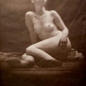 A nude woman in repose looks upward in a sepia-tinged, draped room. The top portion of the image is slightly fuzzy, obscuring the details of her face.