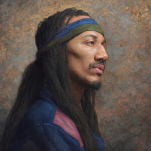 Shoulders-up portrait of a man with long, dreadlocks, a septum ring, a green and blue headband, and a blue jacket with a patch of pink on the shoulder.