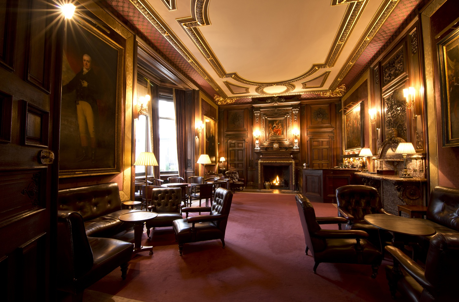 The Savile Club bar: a ceiling with ornate moldings and various places to lounge among paintings and warm lights.