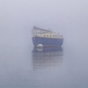 a boat floating in the water on a foggy day.