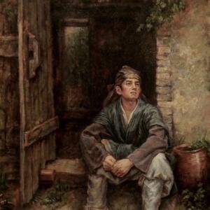An adolescent boy sitting in the doorway of a wooden house.