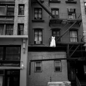 Black and white: a multi-level apartment building with a white dress hanging from the balcony.