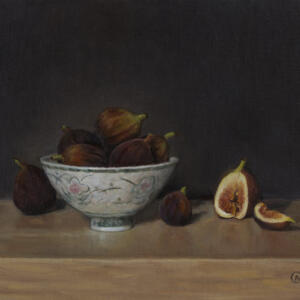A bowl of figs on a wood surface in front of a dark wall.