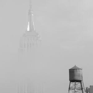 Black and white: the middle section of the Empire State building seems to be invisible due the the cloud covering it on a foggy day.