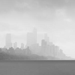 Black and white: the New York City skyline next to the water on a cloudy day.