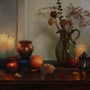 A table with a vase of flowers, lit candles, a peach, an apple, long matches, and a dead flower on a table.